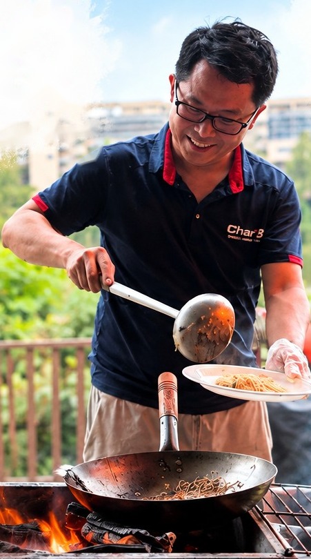 CharB chef plating wok-fried noodles at an outdoor BBQ