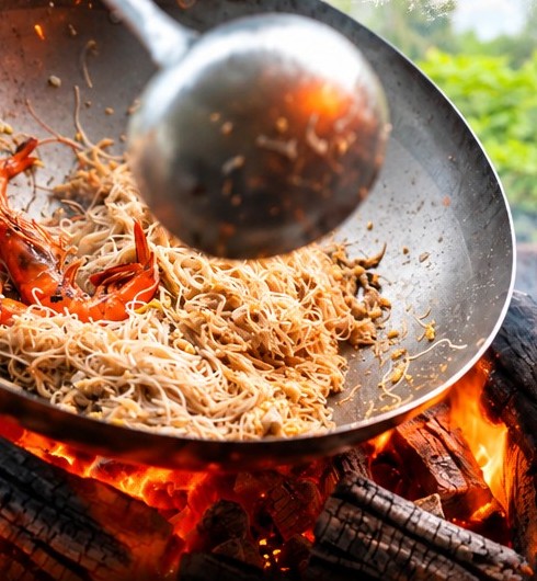 Prawns and mee hoon tossed in a wok over a charcoal fire